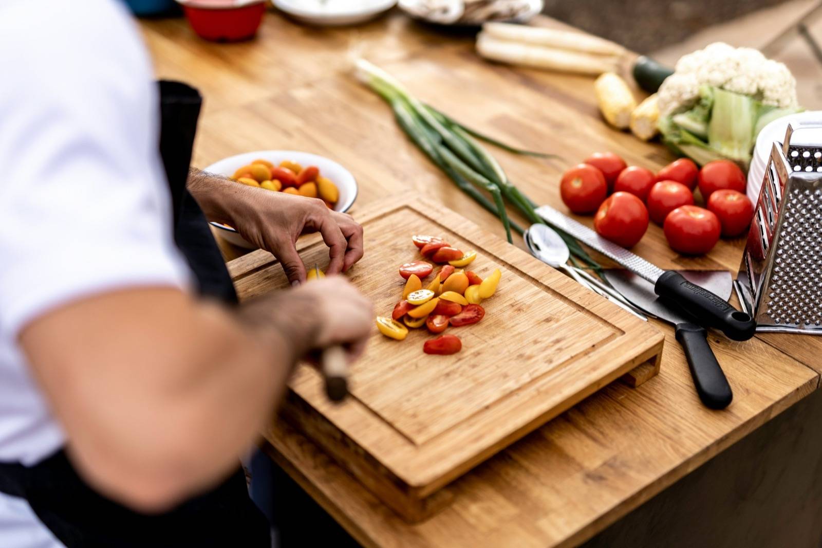 A home cook slicing fresh vegetables on a wooden board